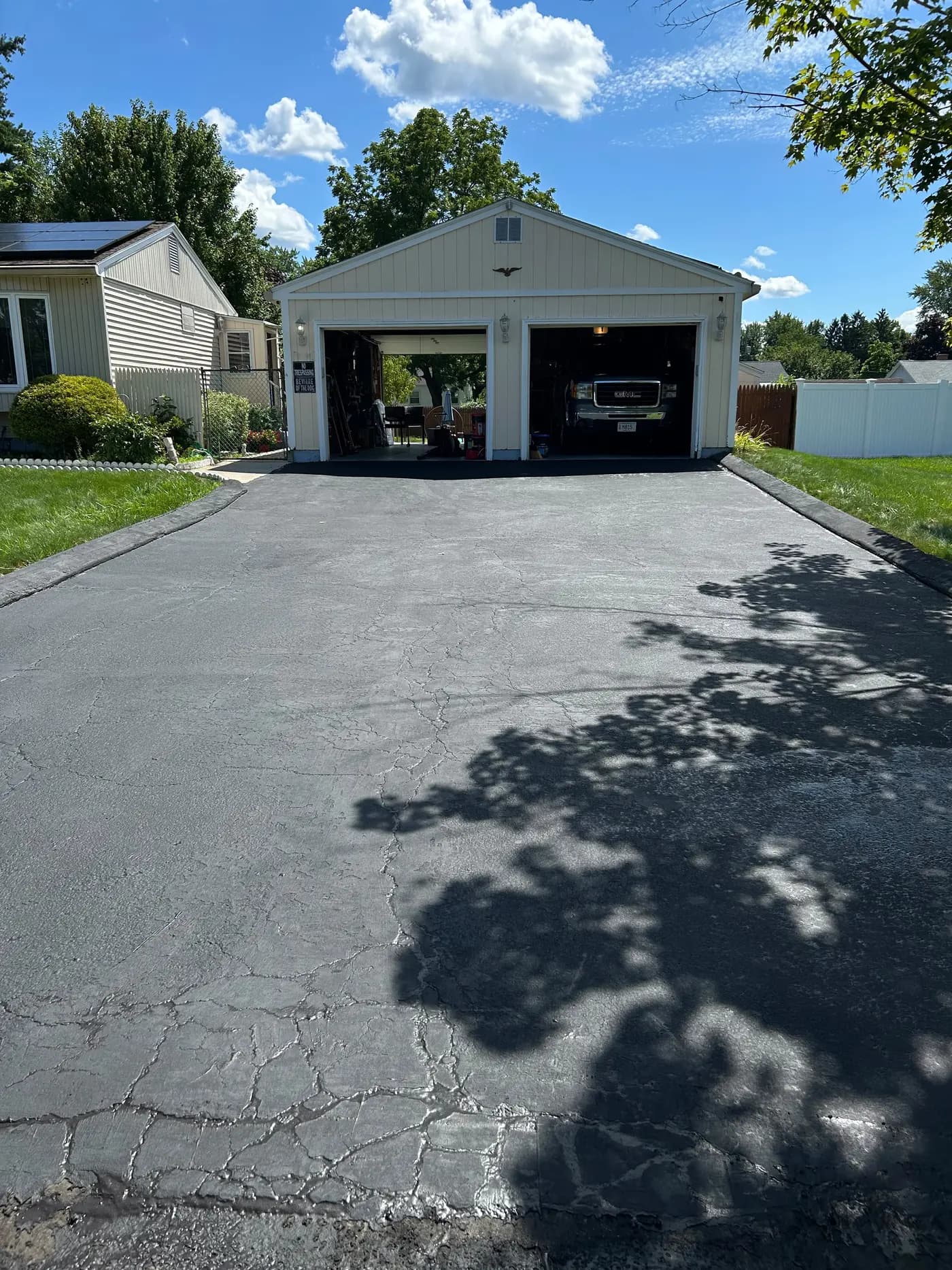 Close-up of a cracked and worn asphalt driveway with faded gray surface needing repair