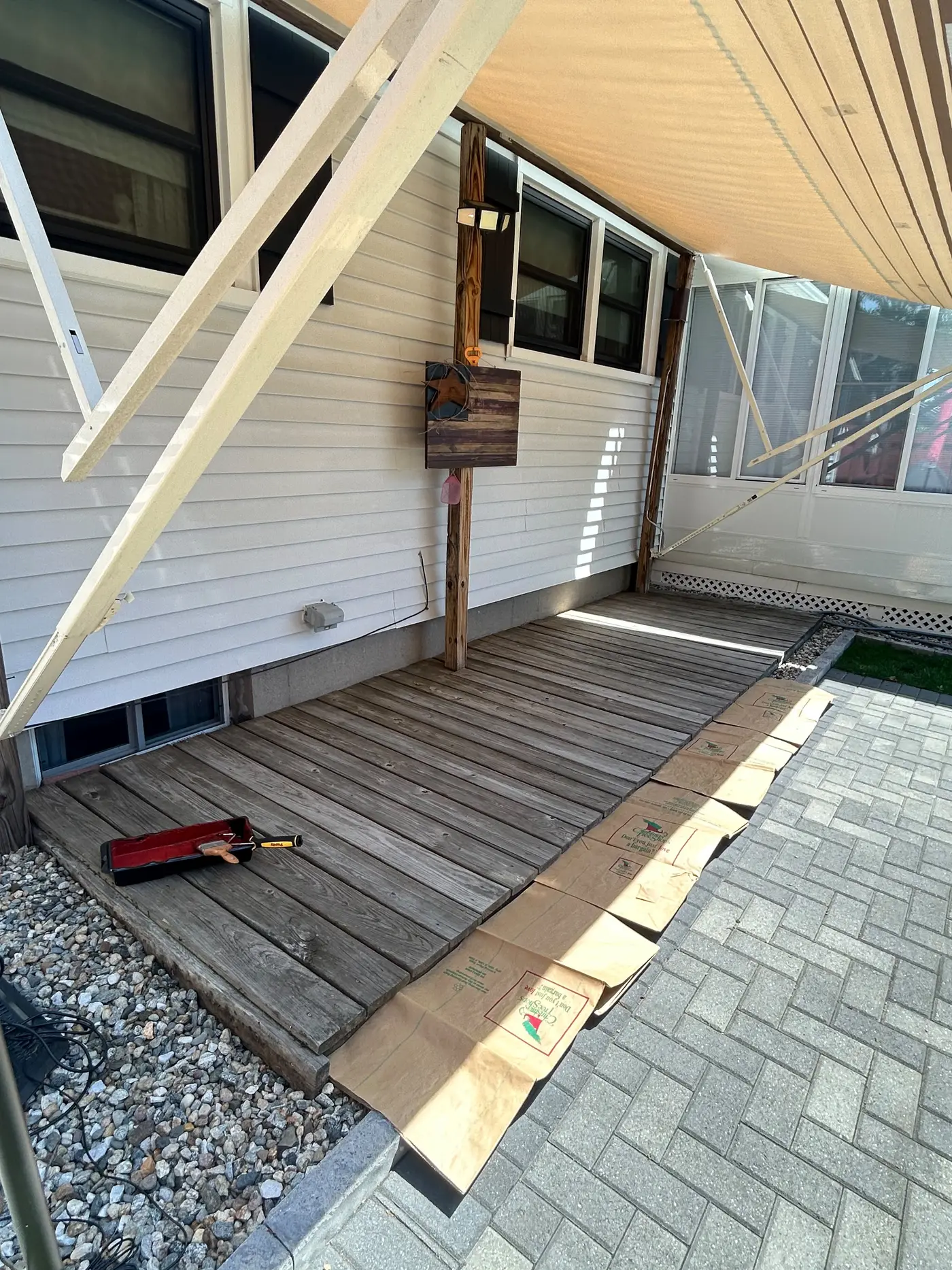 Vinyl house siding being power washed clean, showing a bright section next to a dirty, algae-streaked section